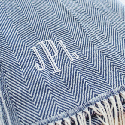 May include: A blue and white chevron patterned throw blanket with white fringe. The blanket has the initials 'J.P.L.' embroidered in white thread.